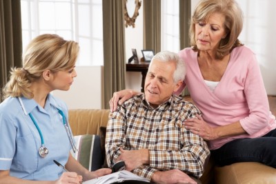 Senior Couple Talking To Health Visitor At Home